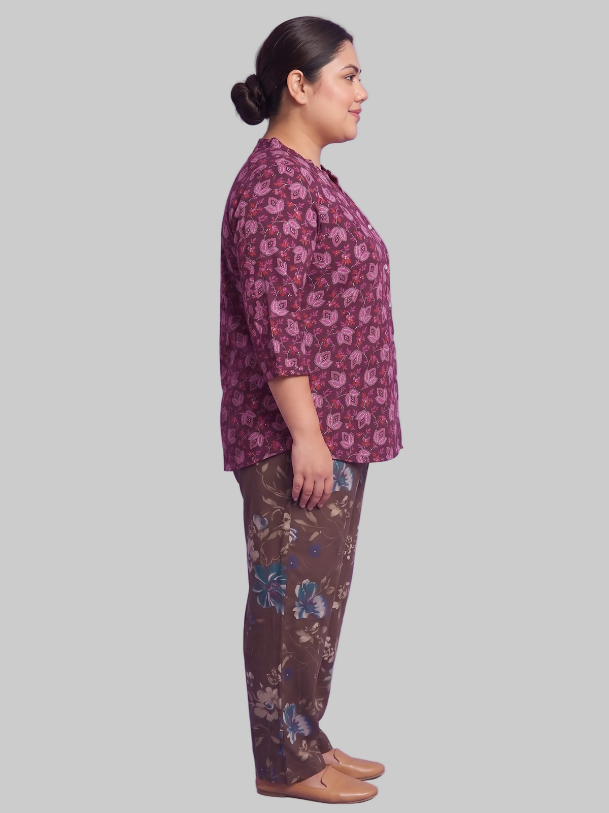Woman wearing a patterned shirt and pants on a purple background