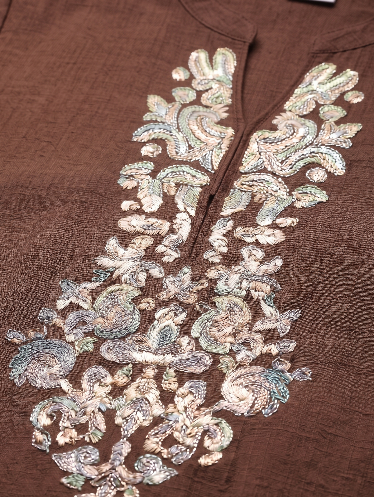 Brown fabric with intricate silver embroidery on a matching brown background