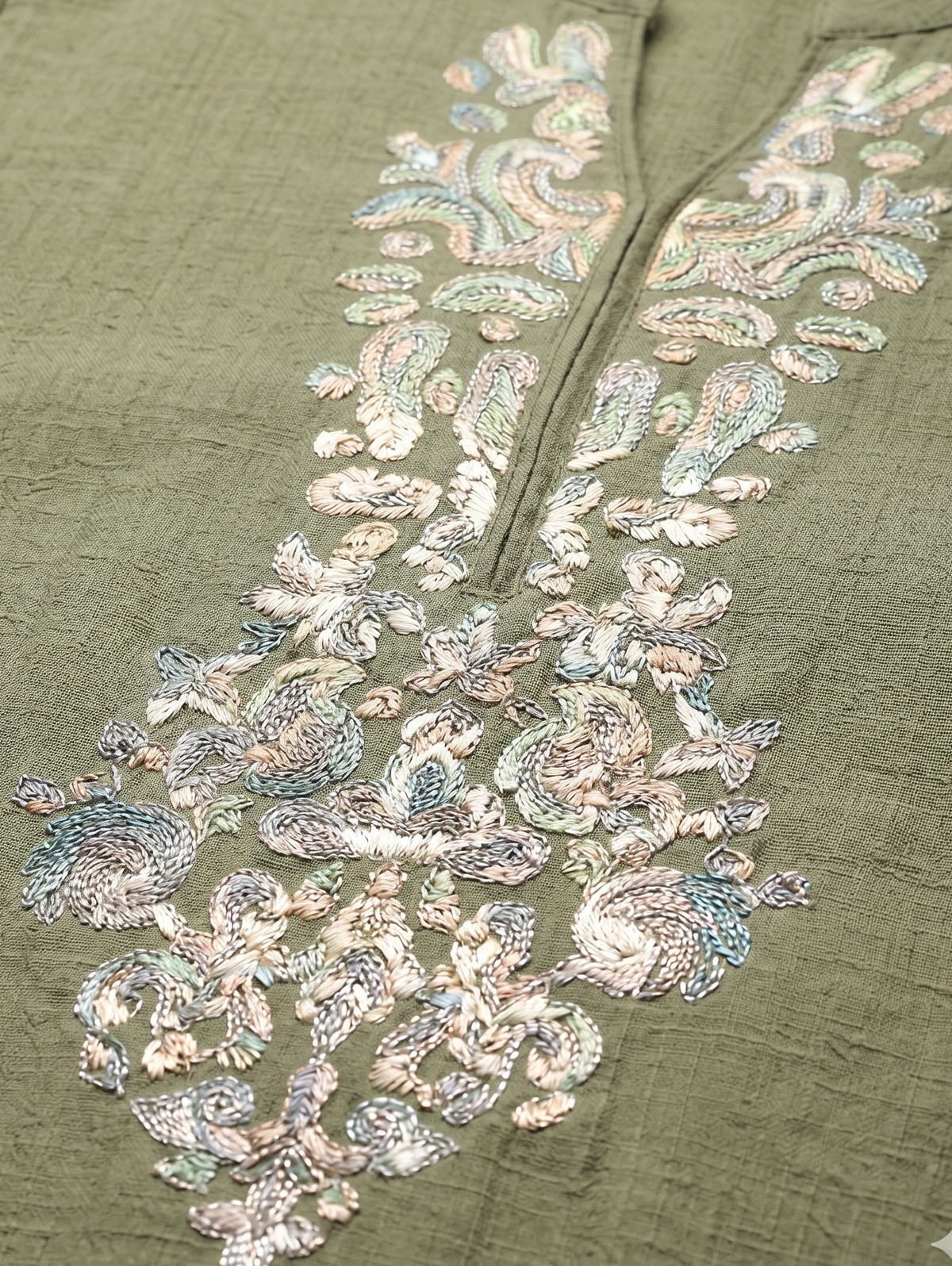 Green fabric with intricate silver embroidery on a matching green background