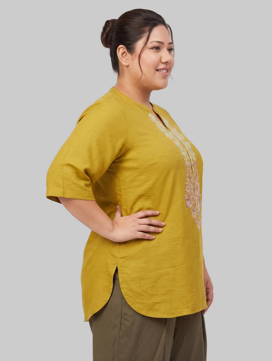 Woman wearing a mustard yellow top with a white background