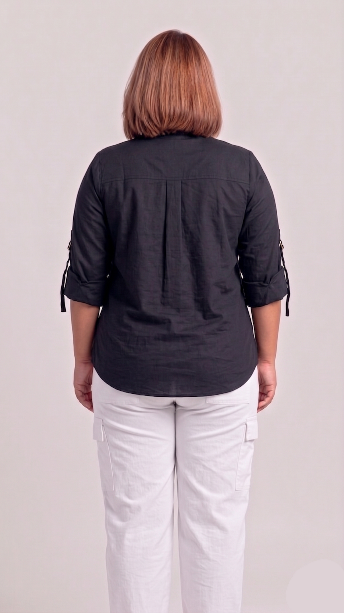 Person wearing a black shirt and white pants on a plain background