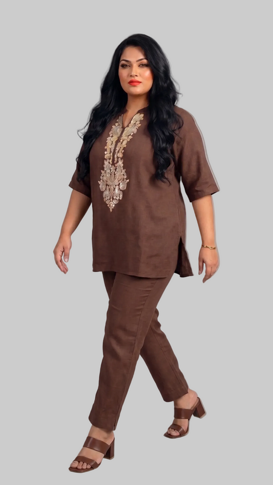 Woman wearing a brown outfit with intricate embroidery on a gray background