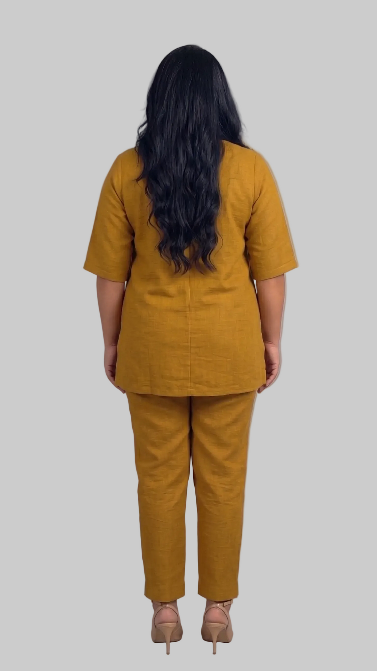 Person wearing a mustard yellow outfit against a gray background