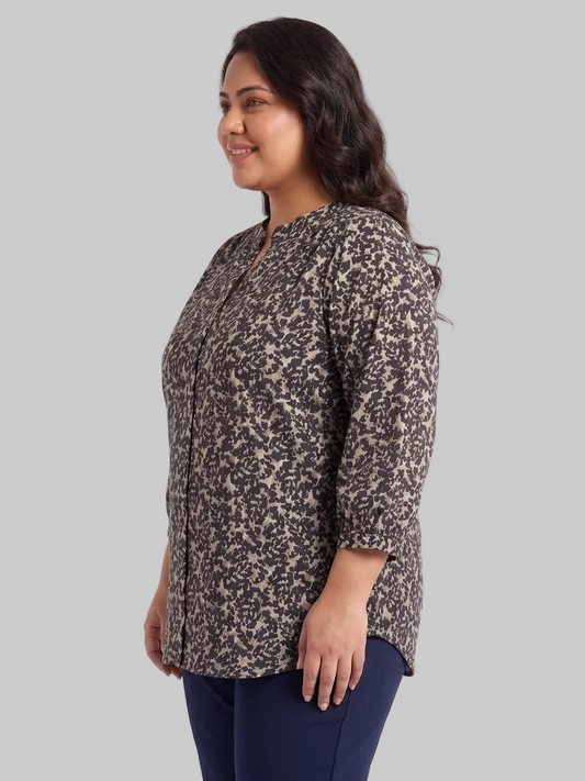 Woman wearing a patterned shirt and blue pants on a white background