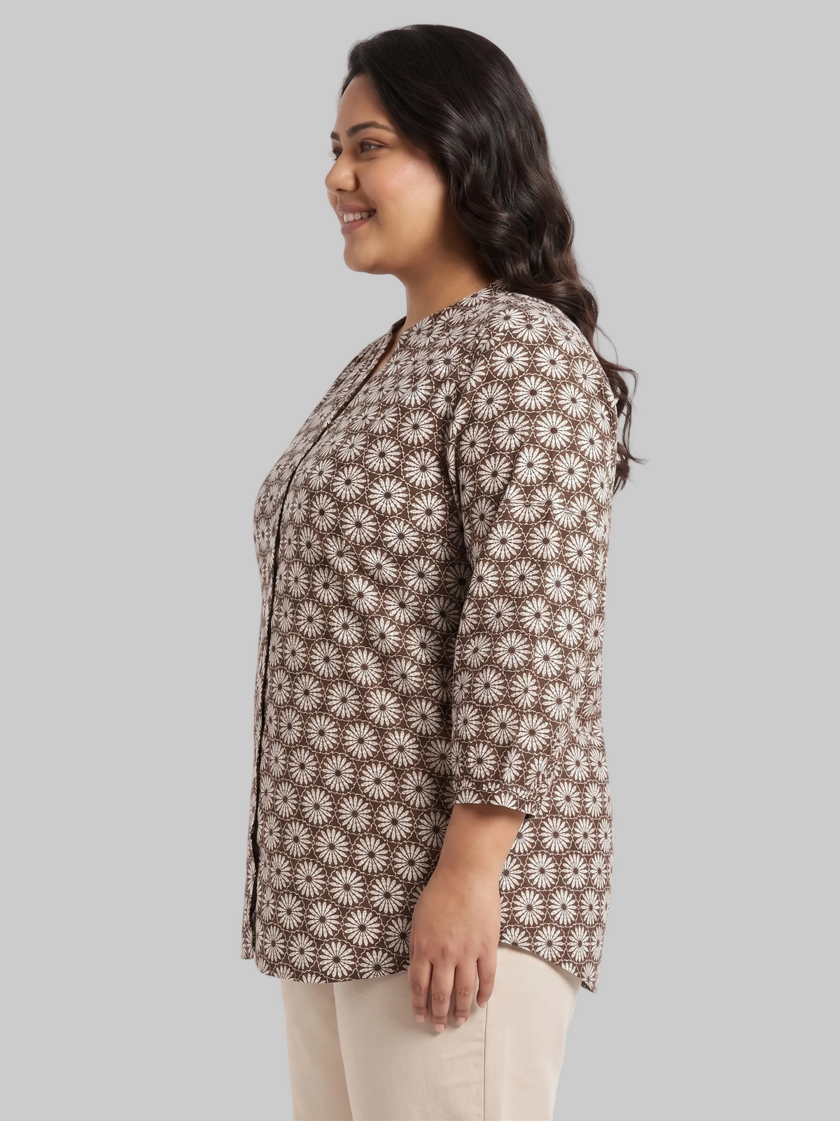 Woman wearing a brown floral patterned shirt on a white background