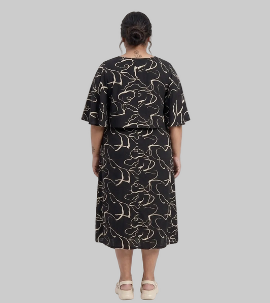 Person wearing a black dress with white patterns on a white background