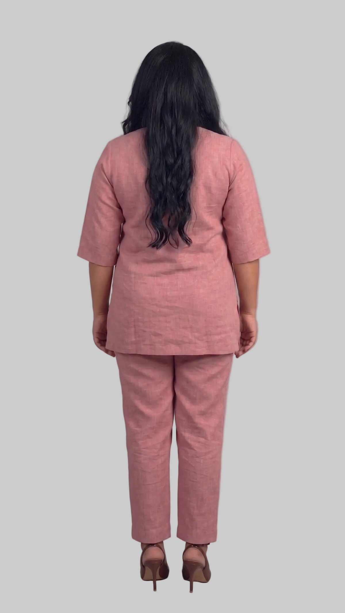Person wearing a pink suit standing against a plain background